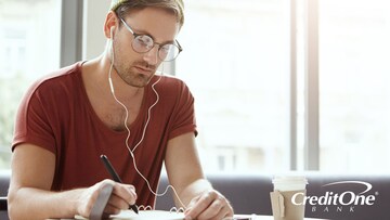 Young man writing his future financial goals in a notebook